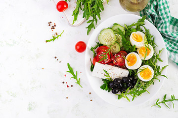 Breakfast. Greek salad and boiled eggs.  Fresh vegetable salad with tomato,  cucumbers, olives, arugula and feta cheese. Trend food. Top view, flat lay