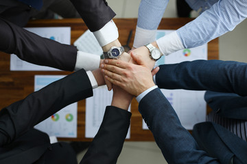 Group men in suits hold out their hands in unity