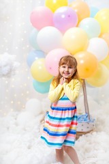 Fototapeta na wymiar dreamy little girl stands in clouds on background with decorative balloon basket