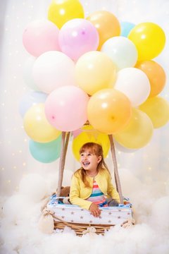 laughing little girl sits in basket decorative balloon and looking away.