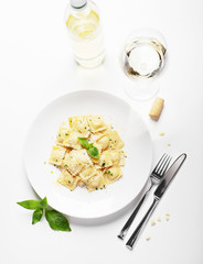 Ravioli with basil and parmesan on a white plate. White wine. Italian Cuisine