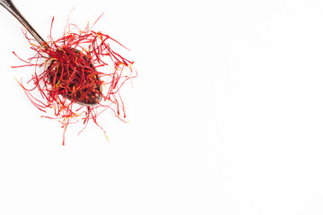 Fototapeta premium Saffron in a metal spoon. Spicy seasoning isolated on white top view.