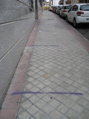 rayas moradas pintadas en acera con dos metros, 2m, de distancia seguridad para filas de  personas junto a coches aparcados. Pobreza, tristeza, soledad