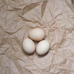 Three chicken beige eggs on the craft paper background.