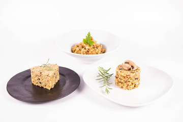 Risotto with button mushroom and bacon - three portions on different plates, on a white background