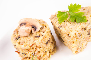 Risotto with button mushroom and bacon - two portions of different shape, on a plate on a white background