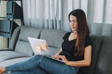 woman sitting on couch at home and make order internet website or shopping online.