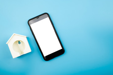 Blank phone and house model on blue background. Top view and Flat lay.