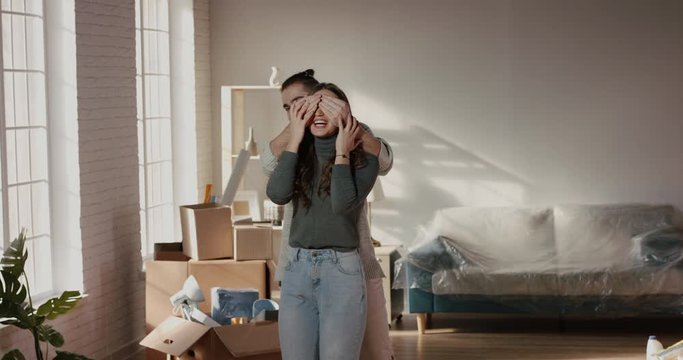 Young caucasian guy is showing his girlfriend their new home. Both are positively smiling and jumping in excitement - new life, young family concept 4k footage