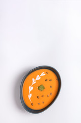 Obraz premium Homemade cream of pumpkin soup with sour cream sauce and pumpkin seeds. White background.
