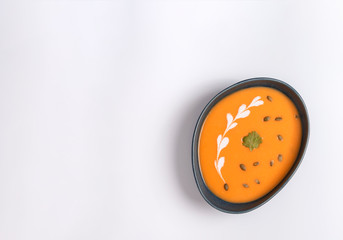 Homemade cream of pumpkin soup with sour cream sauce and pumpkin seeds. White background.