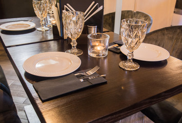 Cafe interior - a table served with plates and glasses, a lit candle, cutlery. A table opposite the...