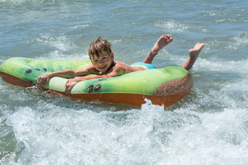 laughing boy of European appearance on an air mattress sways on the waves in the sea. Rest, vacation at sea