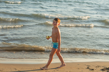 Boy running along the beach during sunset on the sea
