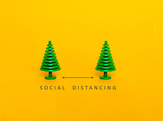 Two figures of a tree on a yellow background. Social distancing in epidemic time concept