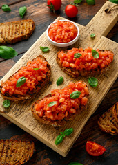 Tomato bruschetta seasoned with basil on a rustic wooden board