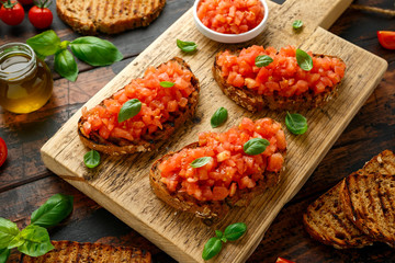 Tomato bruschetta seasoned with basil on a rustic wooden board