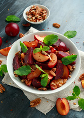Vegan Plum, beet salad with pecan nuts, mint and herbs in white bowl. healthy summer food.