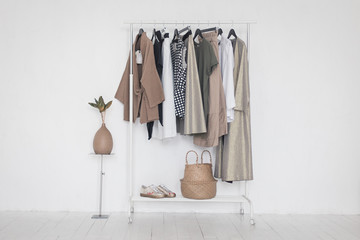 A rack with stylish clothes next to a white wall in the room. Clothing retails concept. Advertise,...