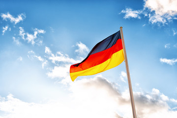 A German flag in front of clouds in blue sky