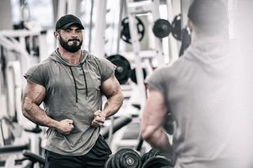 powerful strong young bearded man with beard showing muscle in sport fitness gym