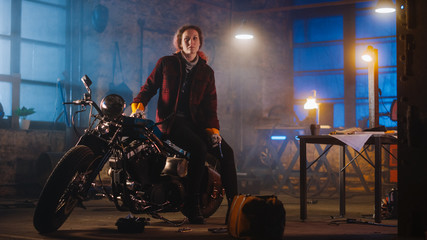 Young Authentic Female Mechanic is Sitting on a Custom Bobber Motorbike and Posing in Workwear with...