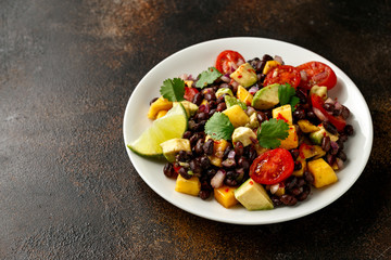 Avocado, mango salad with black bean on white plate