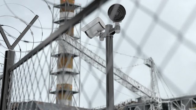 Chernobyl npp behind the fence with barbed wire after nuclear disaster. Nuclear symbol are everywhere and warn of high radiation. CCTV cameras monitoring forbidden zone, restricted area and reactor.