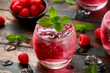 Refreshing raspberry cocktail with ice and mint on wooden table