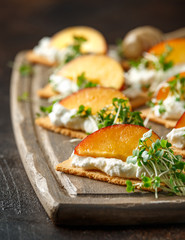 Cottage cheese and nectarine wedges on melba toast appetizers drizzled with runny honey and served with cress salad microgreen. Healthy party finger food