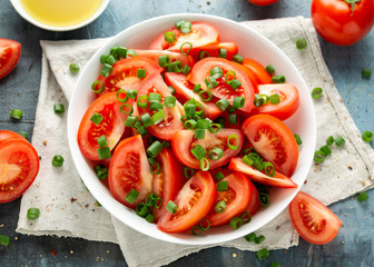 Tomato salad with spring onion and herbs in white bowl. Healthy summer food