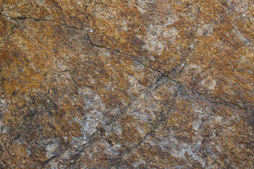 Texture of natural stone. A grey granite stone with cracks and rusty stains.