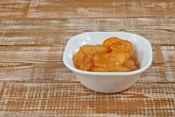 Apple jam in a white bowl on a wooden table. Sweets in utensils on a background of pink wooden boards.