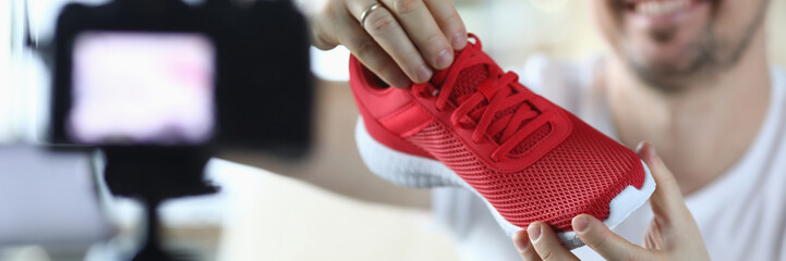 Man holds sneaker in front video camera, overview