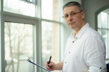 Fototapeta premium A man in a white shirt makes a note in a notebook.