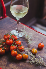 Gourmet ingredientes: cherry tomatoes, rosemary, pepper and white wine glass in a wooden table.