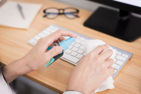 A beautiful Asian businesswoman cleaning a keyboard by cleaner gel and white cloth to protect COVID-19 before start working from home with safety and happiness.