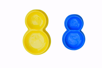 Two double empty plastic pet bowls in blue and yellow on white background. View from above.