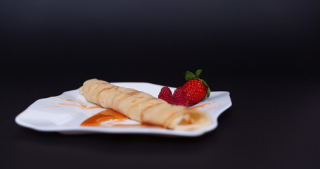 White plate with pancake, jam and fruits