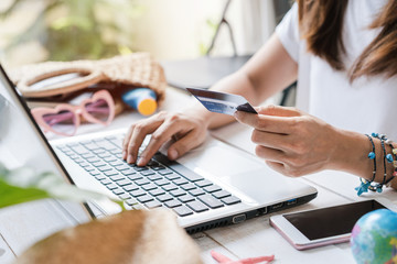 Young women planning summer vacation trip and searching information or booking hotel and using credit card on laptop, Travel concept