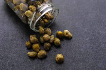pickled capers in a jar on a dark wooden background