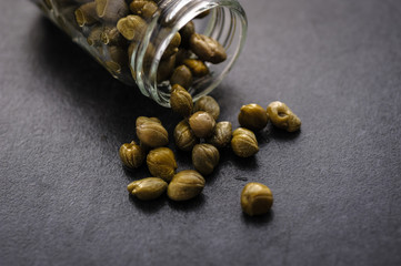 pickled capers in a jar on a dark wooden background
