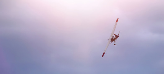 Small plane in the pink and blue sky. Evening. Bad visibility. Banner