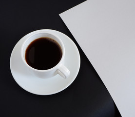 Coffee in a white mug and a sheet of clean white paper. Above, on a black background. Suitable for background. Business. Mockup