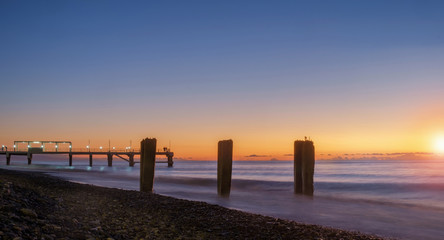 Colorful  sunset on a calm sea with pier at the background