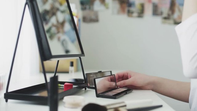 Woman applying makeup by using Brush and palette of cosmetics