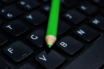 Green pencil on laptop keyboard
