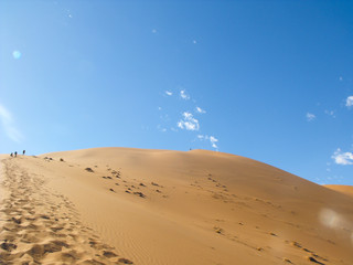 Namib desert on a hot summers day at Sossusvlei close to Sesriem in Namibia climbing and standing on top of the big daddy dune