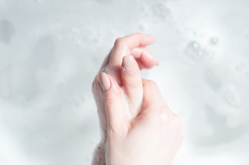 woman washes her hands over water with foam