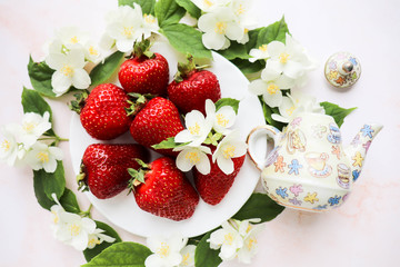 ripe strawberries on a white plate and jasmine flowers. still life